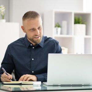 A man takes notes during online training.