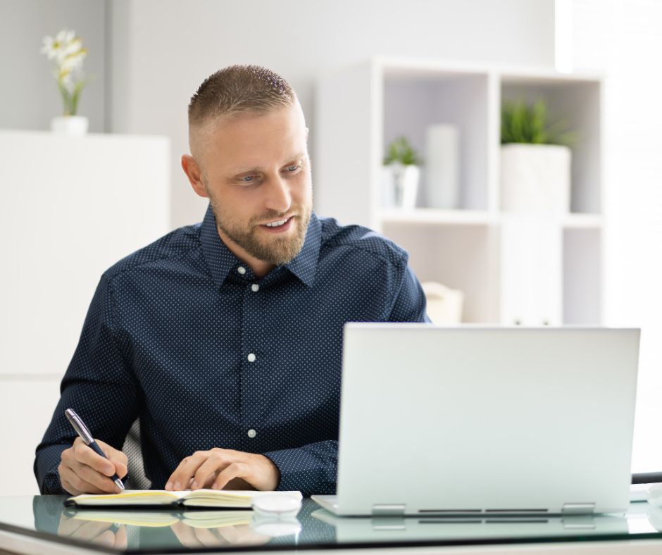 A man takes notes during online training.